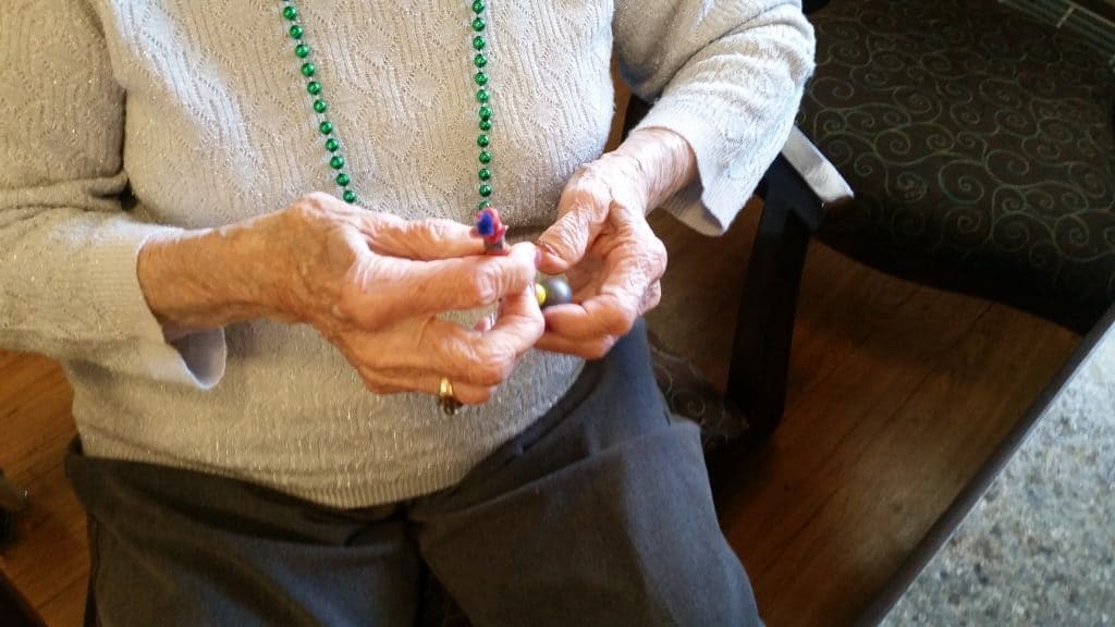 hands of a grandma stringing beads